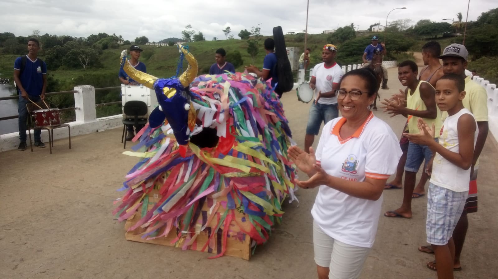 Boi coberto de fitas coloridas dançando na rua com tocadores e público