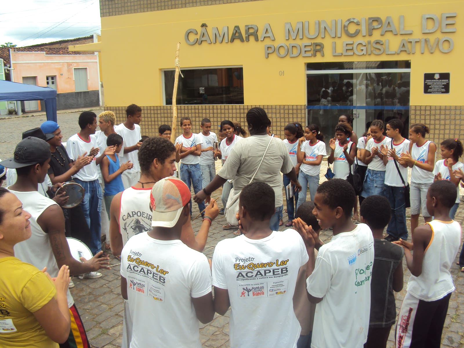 Jovens com camisetas da ACAPEB formando uma roda de samba em frente à Câmara Municipal de Gongogi